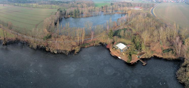 Composite panorama of aerial photographs and aerial photos of two small ponds between meadows and fields with a grill hut and fishing hut, made with drone