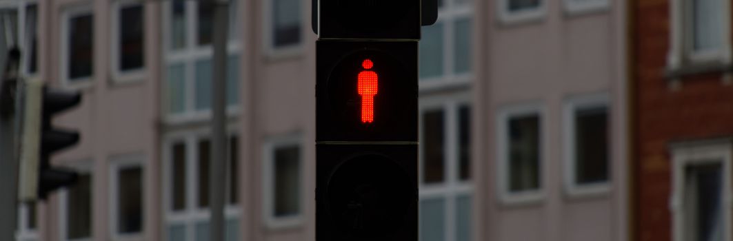 Standstill, red traffic light for pedestrians to stop sign and stop walking, background is blurred by fading depth of field, abstract