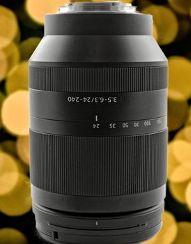 Zoom lens with a focal length of 24 to 240 mm in front of a background with yellow and orange bokeh.