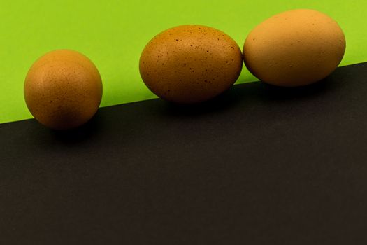 Abstract picture at Easter, three eggs on the oblique borderline of a front black and rear green background, concept