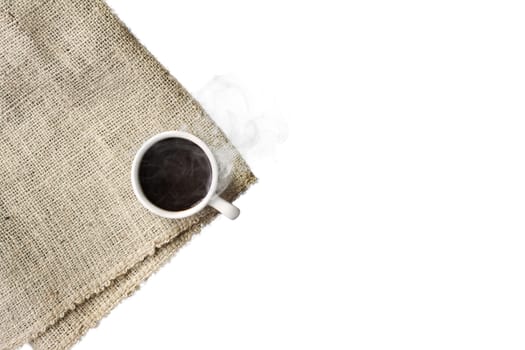 A cup of black coffee with smoke on sackcloth napkin, isolated on white background.