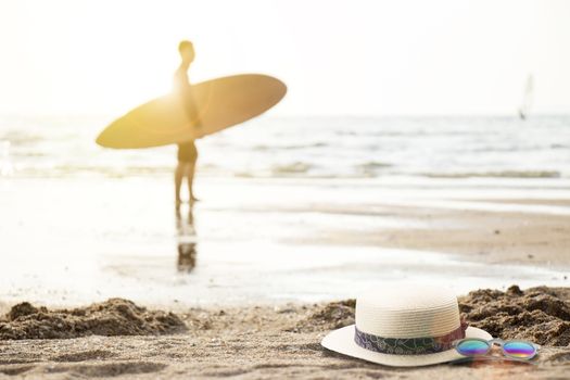 Man with surfboard on the beach at sunset