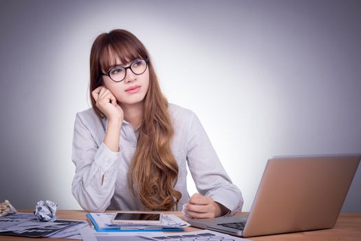 Young Asian office woman at a modern office desk, working with laptop, no concentration with job, feel boring