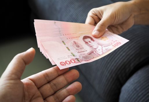 submitting Thai baht banknote money of thailand to hand that is waiting receive, Payment, bribery or sharing concept.
