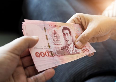 submitting Thai baht banknote money of thailand to hand that is waiting receive, Payment, bribery or sharing concept.