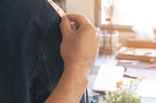 Fashion designer design new jean jacket with model. Seamstress measure shoulder jacket on model. Tailor man measure new jean jacket at workshop.  