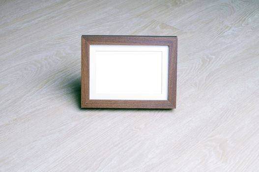 Empty picture wood frame on wood laminate floor. Copyspace for text. Picture frame Mock up 