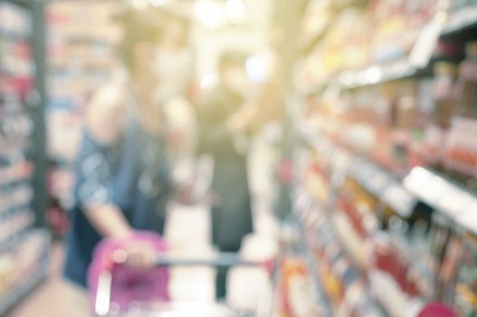 Blur woman use shopping cart in supermarket. Asian woman shopping food materials in Departmenstore. Blur background. 