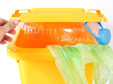 Yellow trash, plastic bottle and green bag in bin, Garbage dumping into trash helps to clean.
