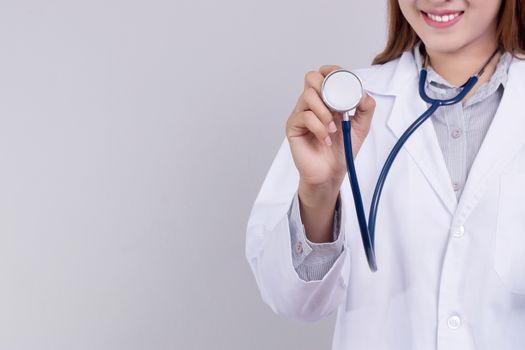 Young Asian woman doctor holding a stethoscope with smile face standing isolated on gray background. healthy care concept