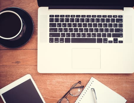 Flat lay, Close up Clean Open Notebook, paper, Tablet, glasses, coffee on Top of Wooden Table with retro color filter effect. Business concept.