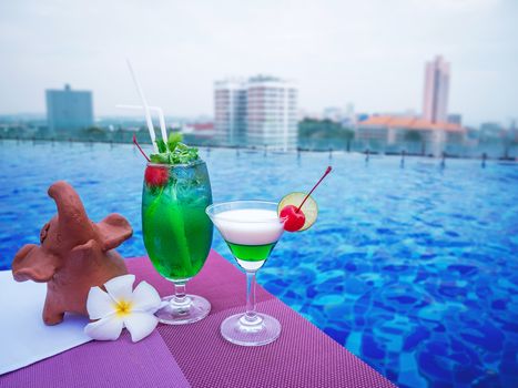 Cocktail glasses at swimimg pool with city view