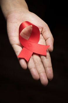 Red ribbon awareness on woman human hand : World aids day satin ribbon symbolic concept raising concerns/ help campaign on people health public support on HIV STD heart disease