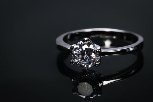 luxury wedding ring with big diamond crystal isolated on black background with reflect in the mirror.