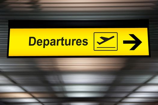 Airport departure sign hanging from airport ceiling