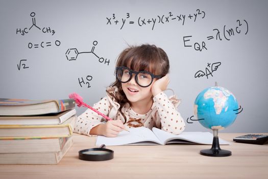 education concept. cute little girl at school happy to making homework. mathematical equations and chemical formula in background