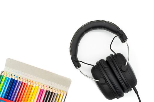 24 crayon colors, packed in a box, placed in the bottom left corner of the picture and the headphones are in the bottom right corner and all are on a white background.