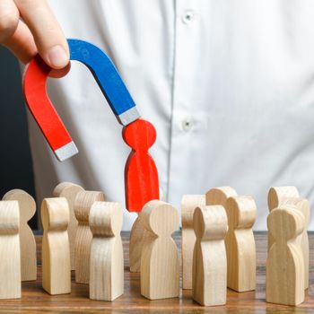 businessman pulls out a red figure of a man from the crowd with the help of a magnet. leader manages the business and forms a team. Increase team efficiency, productivity. toxic, non-competent worker.