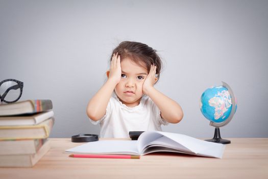 little cute girl suffering from headache while doing overwork with learning , homework , study and exam. school children education habit and parent concern concept.