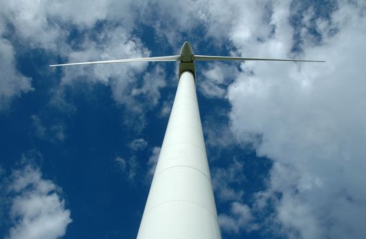 A view of a white wind generator from the ground