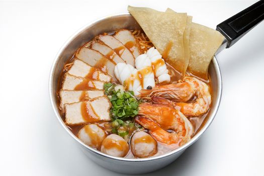 Pot of spicy instant noodles with red sauce isolated on white background. Topping with fried dumplings, seafood , shrimp, squid, tofu slide , pork ball and coriander