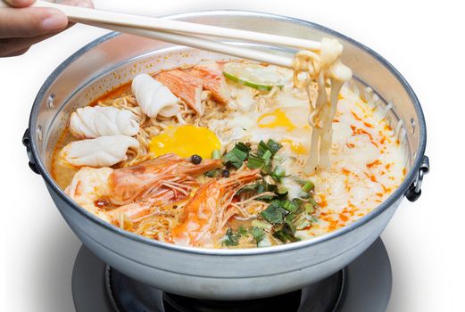 Pot of spicy instant noodles with Cheese isolated on white background. Topping with egg , seafood , shrimp, Squid, crab ,lemon and coriander.Chopsticks