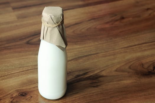 Hot fresh milk in a glass bottle on wooden background