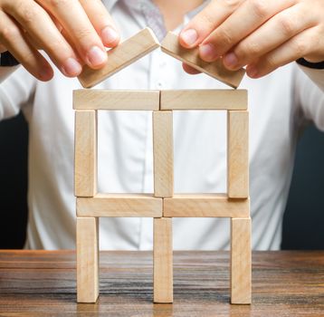 A man completes a building of dominoes. Expansion and development. Creating a business, startup. company protection, support for small and medium-sized businesses. Insurance assistance