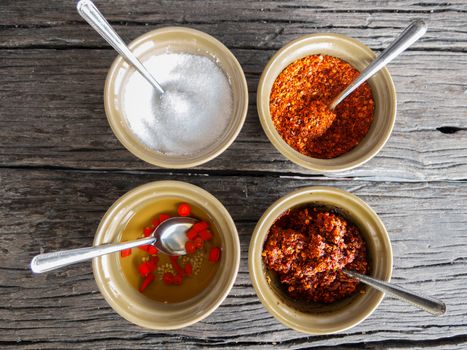 food flavoring concept. sugar , cayenne pepper, vinegar and chili paste in small bowl for food flavoring on wooden table background