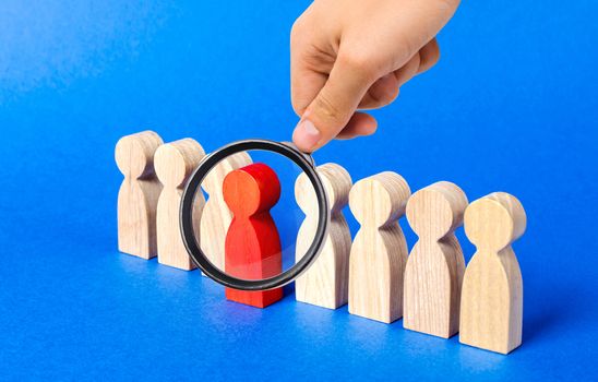 A magnifying glass looks at a red figure person comes out of people line. Leadership qualities, talented employee. HR is looking for new employees, choice among candidates. A suitable candidate