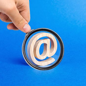 A magnifying glass looks at a email icon on blue background. internet correspondence. Contacts for business. Business tools. Internet and global communication, digitalization of economy. at commercial