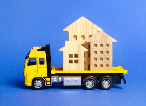 A cargo truck transports houses. Concept of transportation and cargo shipping, moving company. Construction of new houses and objects. Logistics and supply. Move entire buildings