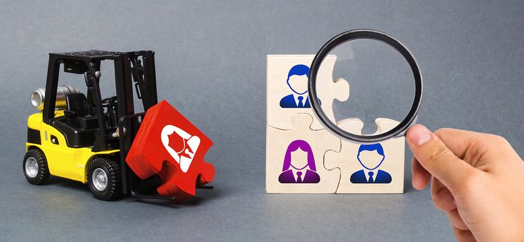 A magnifying glass looks at a red puzzle to the unfinished assembly of business team. Search, recruitment staff, hiring leader. Creating an efficient and productive business unit. Leadership