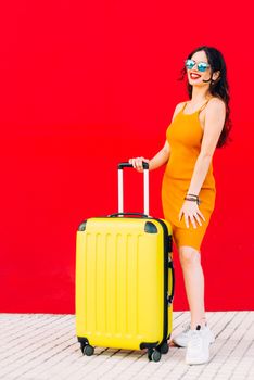 happy woman holding suitcase and smiling while standing.