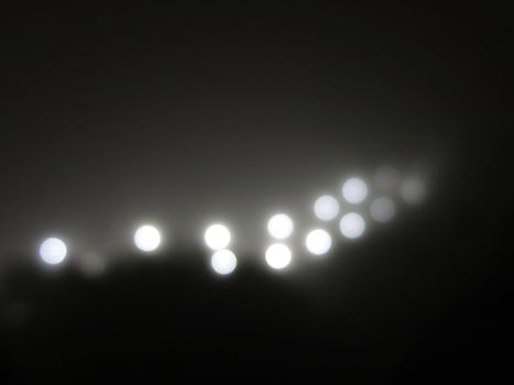 Abstract lights in the fog. Ray of bright white light from a street lamp in the fog. black and white