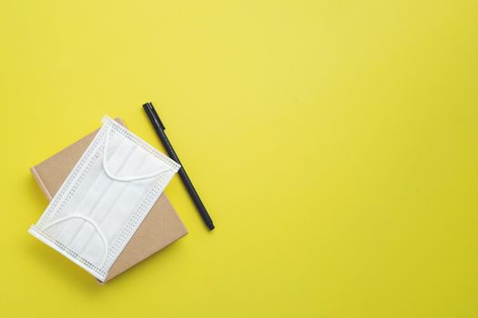 Hygiene face mask with office supply as notebook and a pen for new normal or new way of living concept