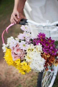 young beautiful romantic black and white couple people holding hand together on bicycle in garden street with colorful bouquet flowers in bicycle basket. romantic relationship ,happy, wedding, together in love, date