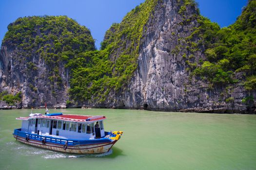 Popular famous tourist attraction in Vietnam. Tourist junk boat floating among limestone rocks at Halong Bay, Hanoi , South China Sea, landmark of Vietnam, Southeast Asia