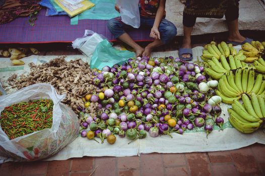 Street vendor selling fresh vegetables in Luang Prabang morning market in Laos