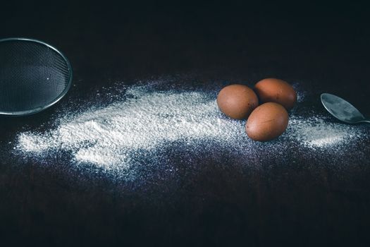 Conceptual still life photo of eggs and flour spilled on a table to show concept of baking as a way to support mental health and coping during home quarantine due to covid-19 pandemic