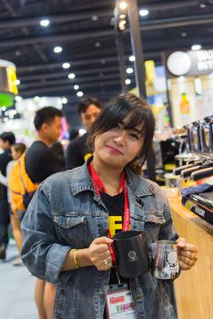 Bangkok, Thailand - June 3, 2017 : Unidentified woman barista pouring latte froth to make a coffee latte art into the white coffee cup for serve to customers in the coffee shop.