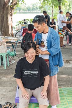 Bangkok, Thailand - July 28, 2017 : Unidentified Thai woman to take of service Thai massage by wooden hammer for treat aches and pains. The service comes in the outdoor garden.