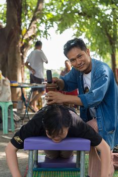 Bangkok, Thailand - July 28, 2017 : Unidentified Thai woman to take of service Thai massage by wooden hammer for treat aches and pains. The service comes in the outdoor garden.