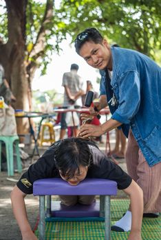 Bangkok, Thailand - July 28, 2017 : Unidentified Thai woman to take of service Thai massage by wooden hammer for treat aches and pains. The service comes in the outdoor garden.