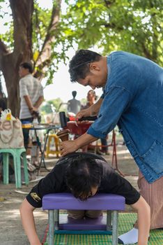 Bangkok, Thailand - July 28, 2017 : Unidentified Thai woman to take of service Thai massage by wooden hammer for treat aches and pains. The service comes in the outdoor garden.