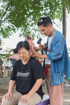 Bangkok, Thailand - July 28, 2017 : Unidentified Thai woman to take of service Thai massage by wooden hammer for treat aches and pains. The service comes in the outdoor garden.