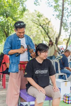 Bangkok, Thailand - July 28, 2017 : Unidentified Thai woman to take of service Thai massage by wooden hammer for treat aches and pains. The service comes in the outdoor garden.