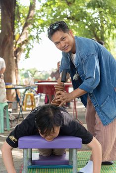 Bangkok, Thailand - July 28, 2017 : Unidentified Thai woman to take of service Thai massage by wooden hammer for treat aches and pains. The service comes in the outdoor garden.