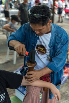 Bangkok, Thailand - July 28, 2017 : Unidentified Thai woman to take of service Thai massage by wooden hammer for treat aches and pains. The service comes in the outdoor garden.