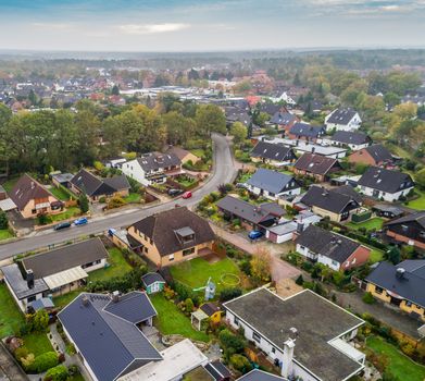 Suburban settlement in Germany with terraced houses, home for many families, aerial photograph taken at a slanting angle with the drone, dramatic sky